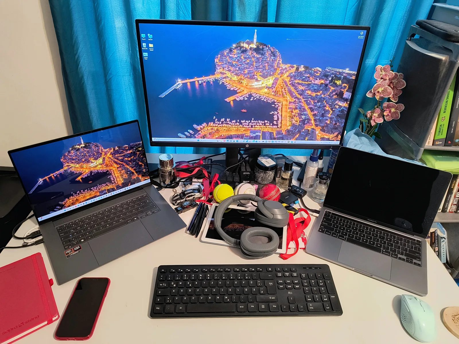 The desk as it is right now – two laptops, the main monitor, headphones and an orchid
